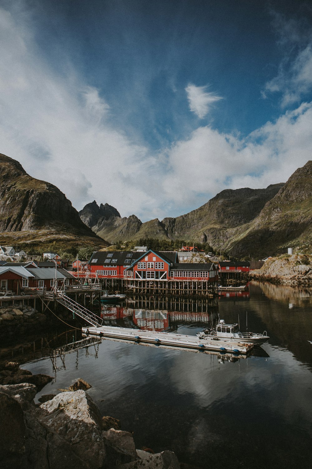 a boat dock with a red building and mountains in the background