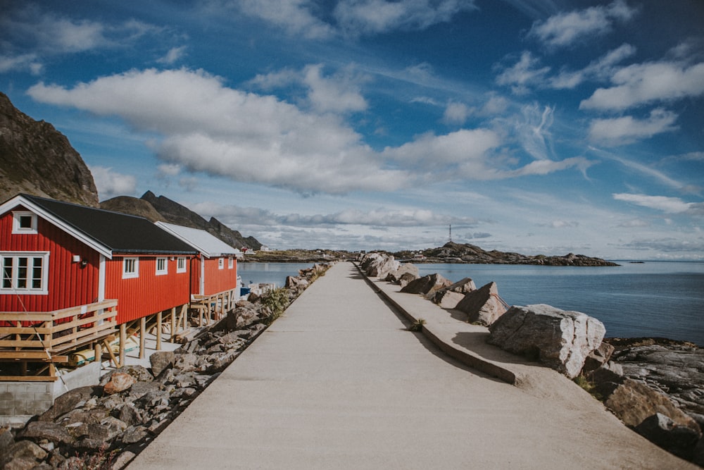 a red house sitting on top of a pier next to a body of water