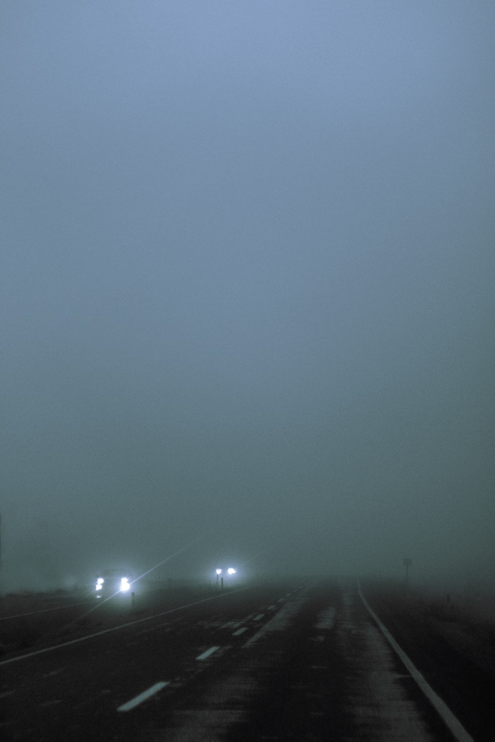 a foggy highway with two cars driving on it