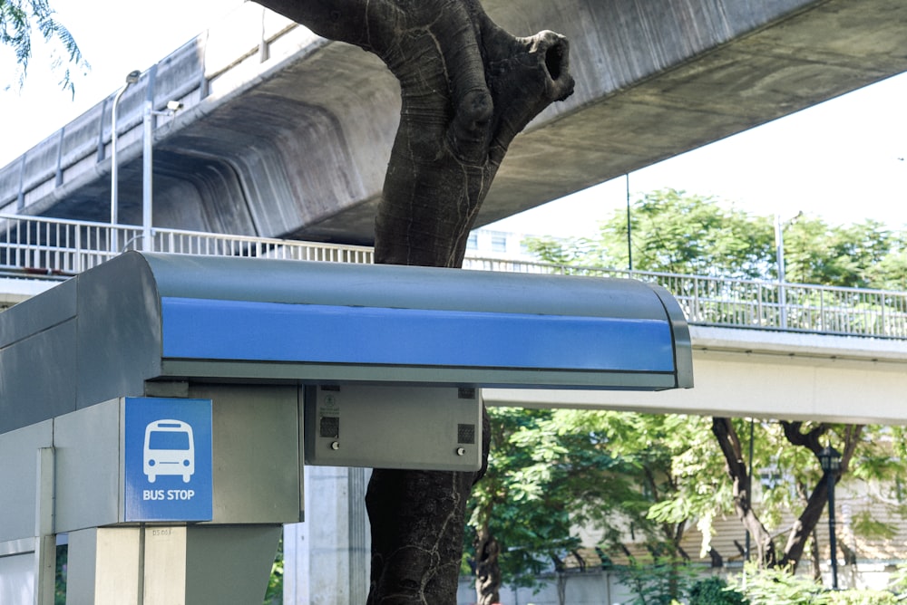 a blue and white mailbox under a bridge