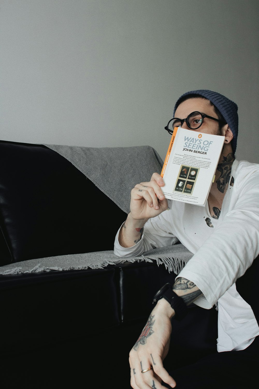a man sitting on a couch holding up a book