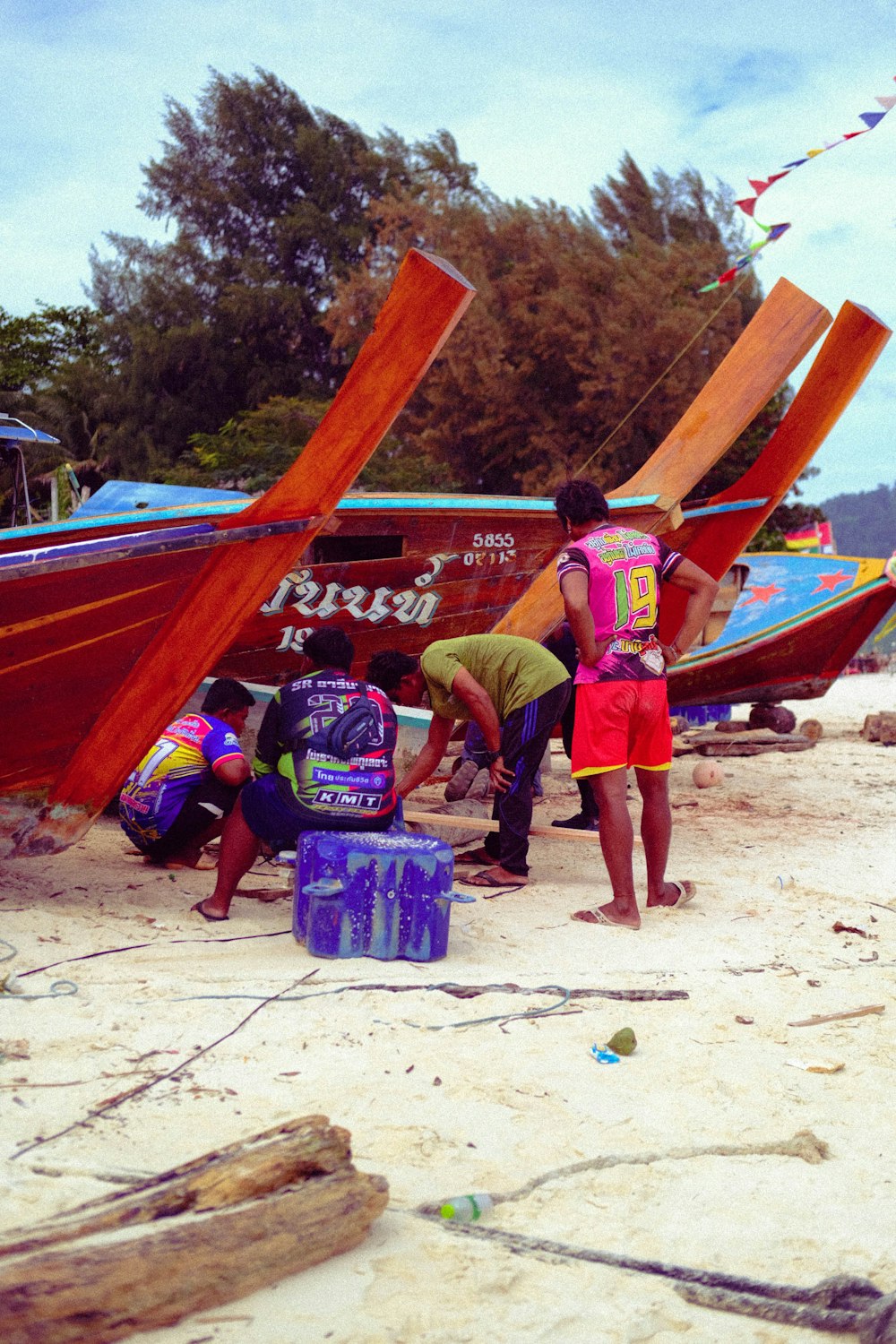 a group of people standing around a boat on the beach