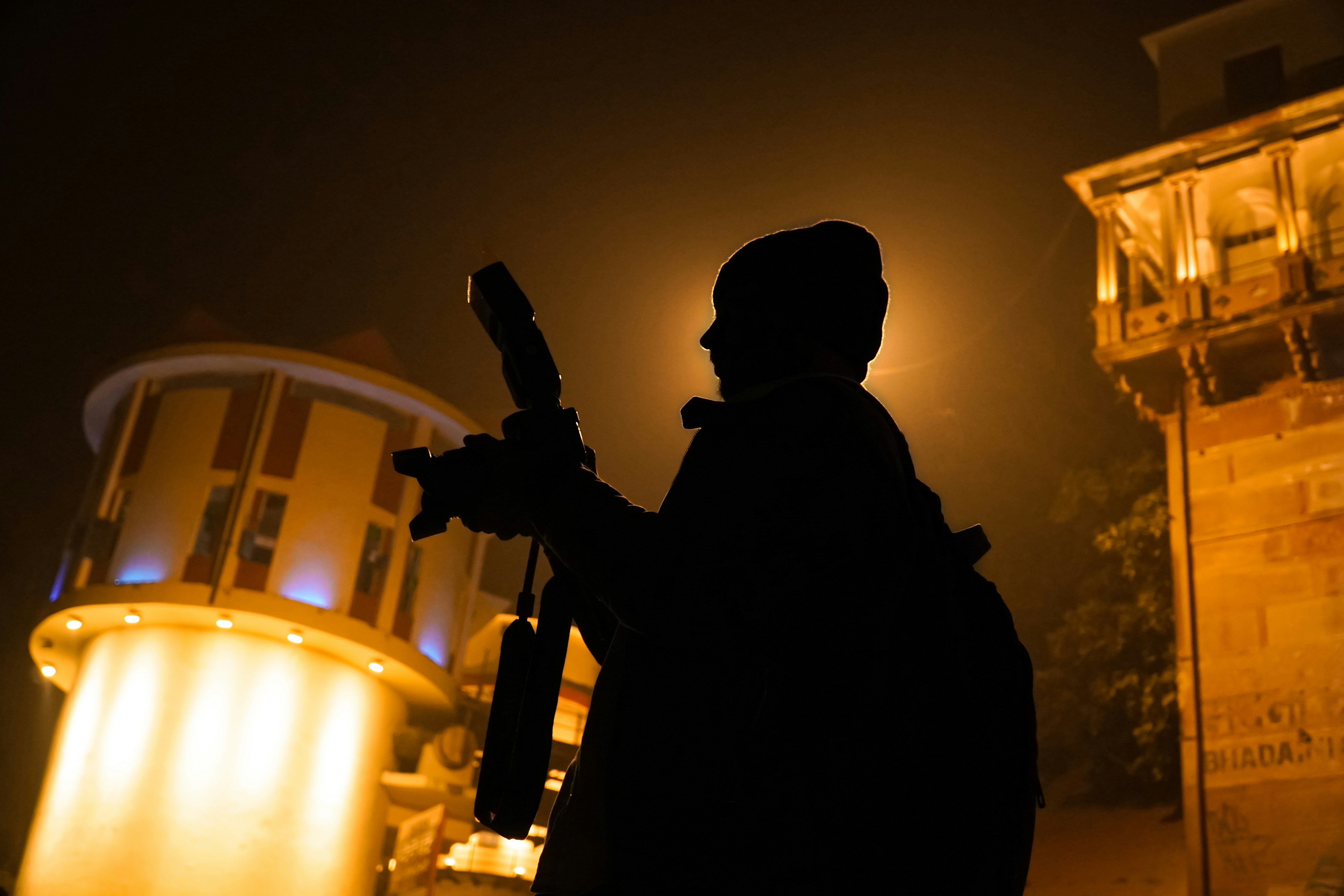 Man Holding camera at street at night.
