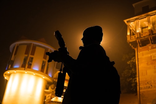 a silhouette of a person holding a gun in front of a building