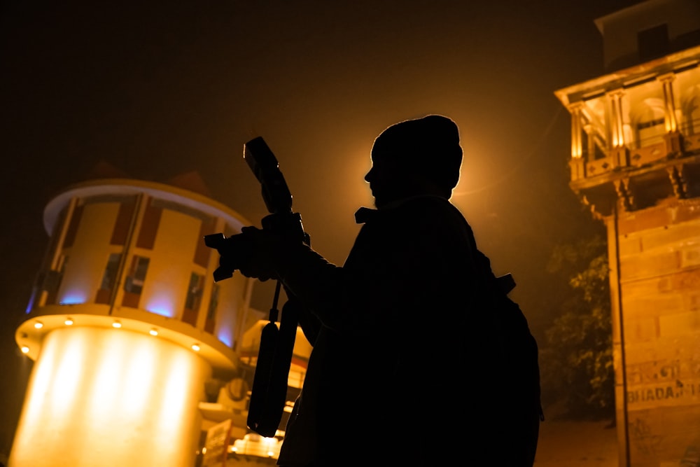 a silhouette of a person holding a gun in front of a building