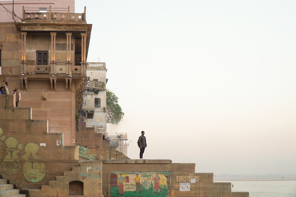 a man standing on top of a building next to a body of water