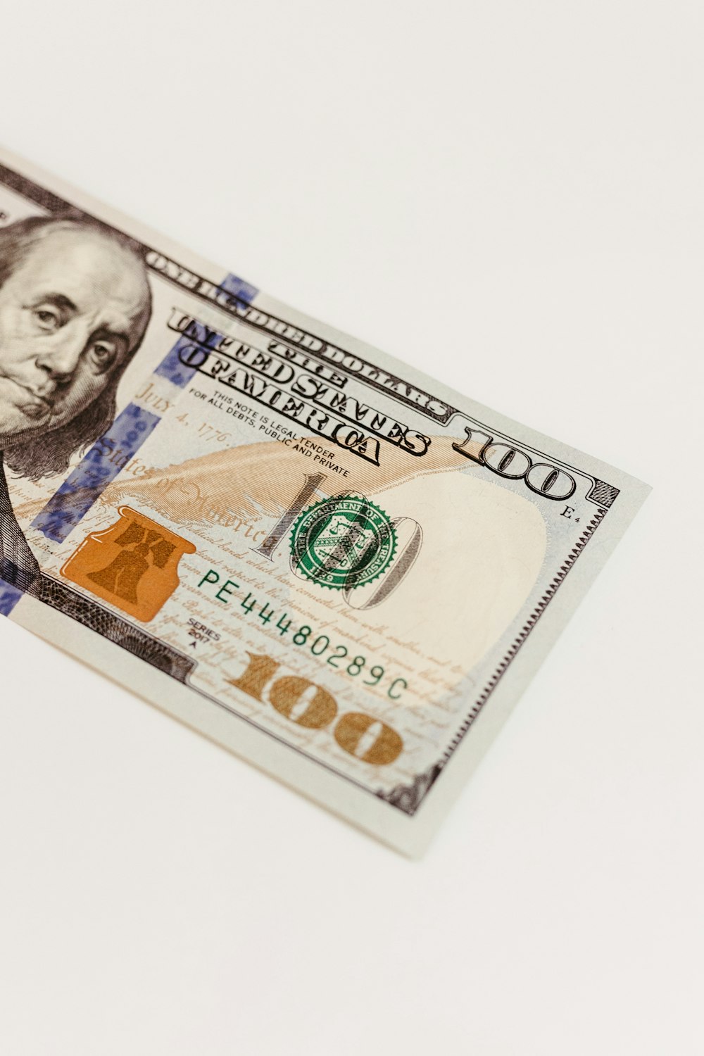 un billet de cent dollars posé sur une table blanche