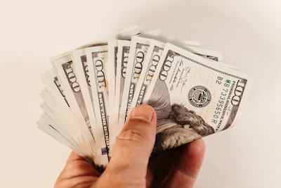 a hand holding a bundle of twenty dollar bills