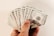 A hand holding a fan of hundred US dollar bills, displaying multiple notes in a splayed arrangement. The bills are crisp and new, showcasing the detailed design and printing.