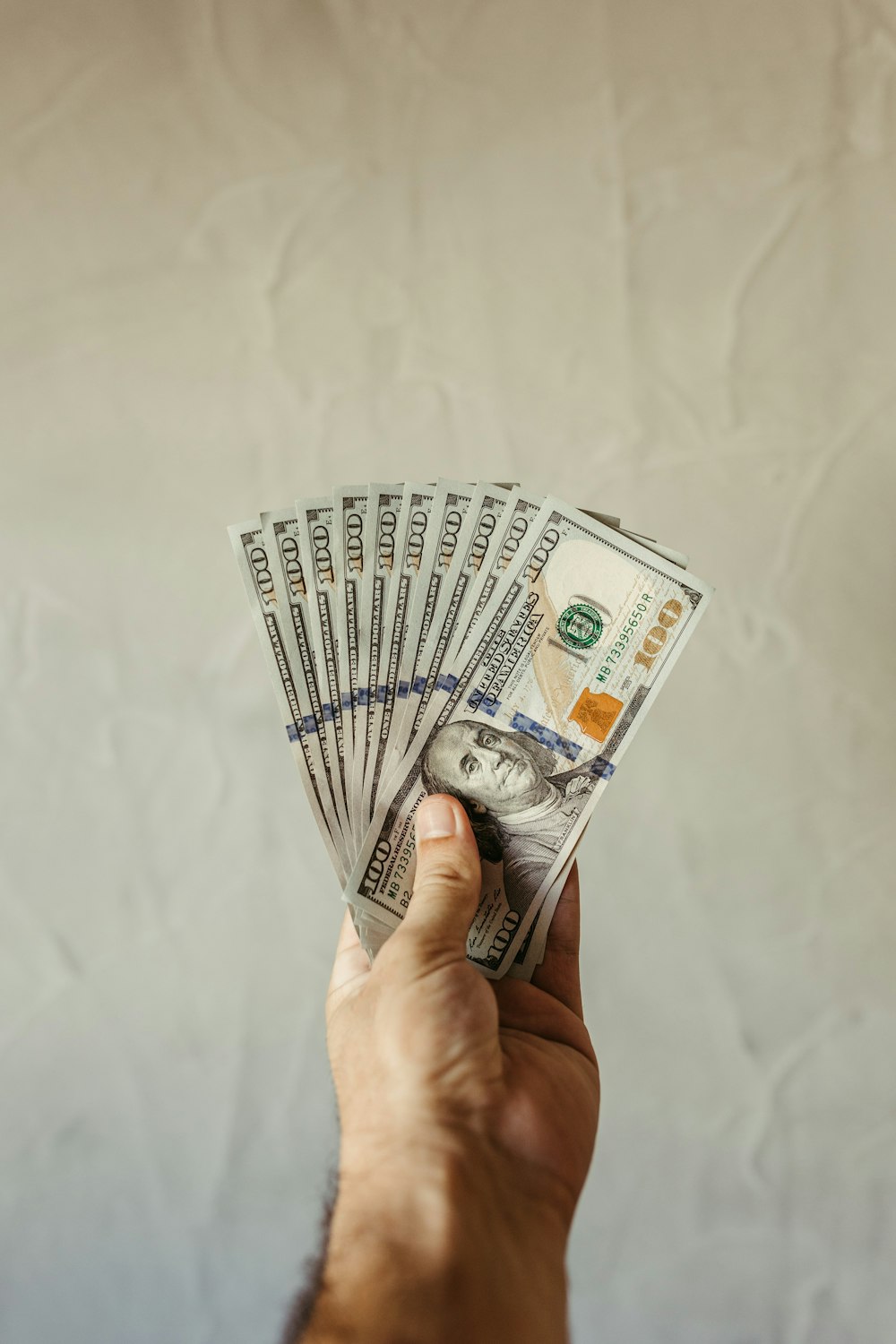 a hand holding a stack of twenty dollar bills