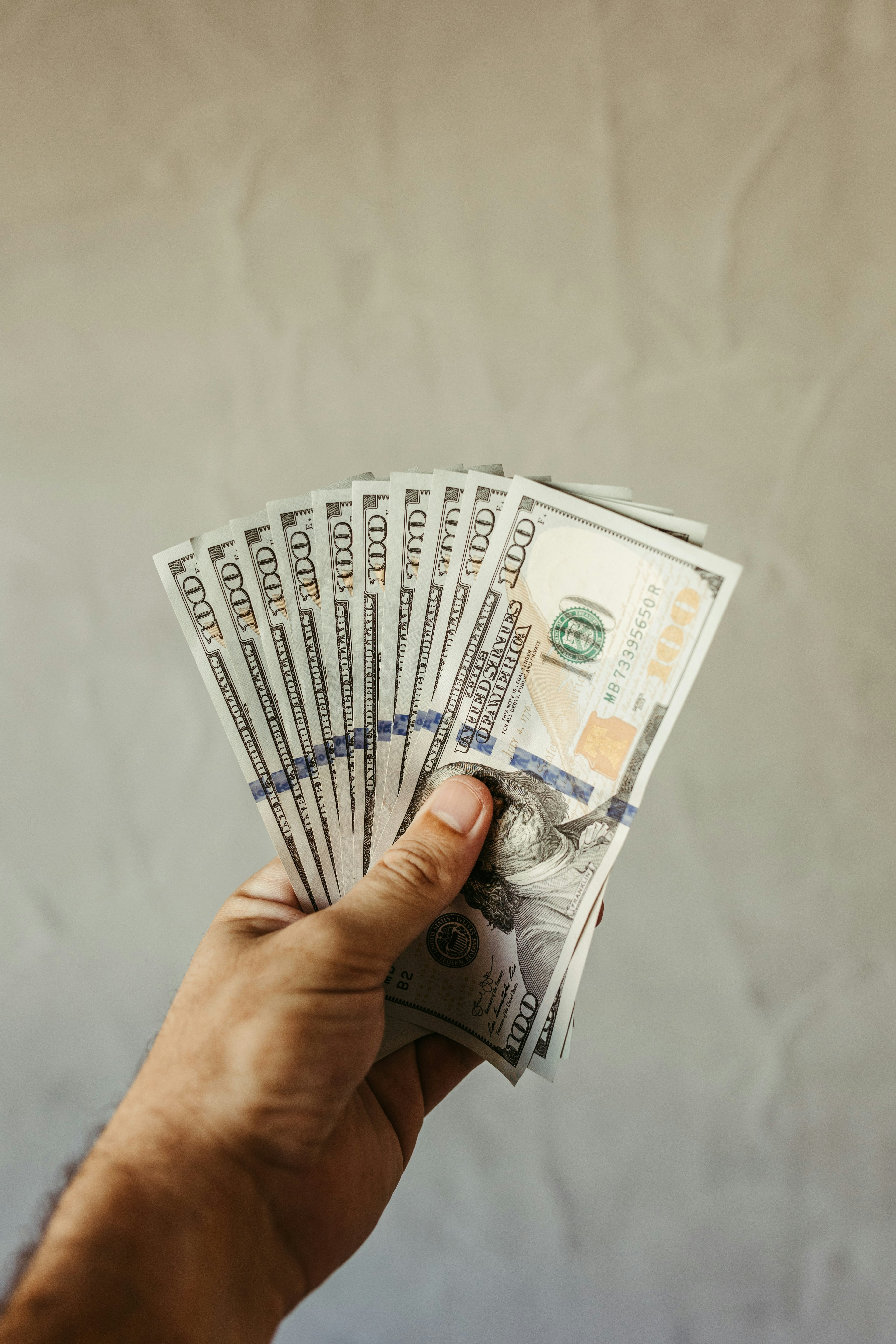 a hand holding a stack of twenty dollar bills