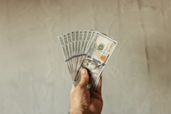 a hand holding a stack of twenty dollar bills