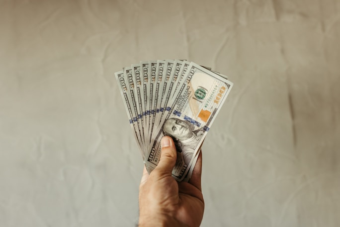 a hand holding a stack of twenty dollar bills