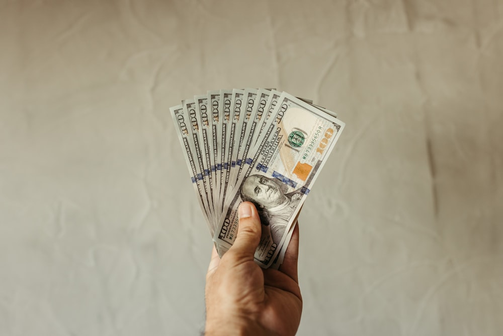 a hand holding a stack of twenty dollar bills