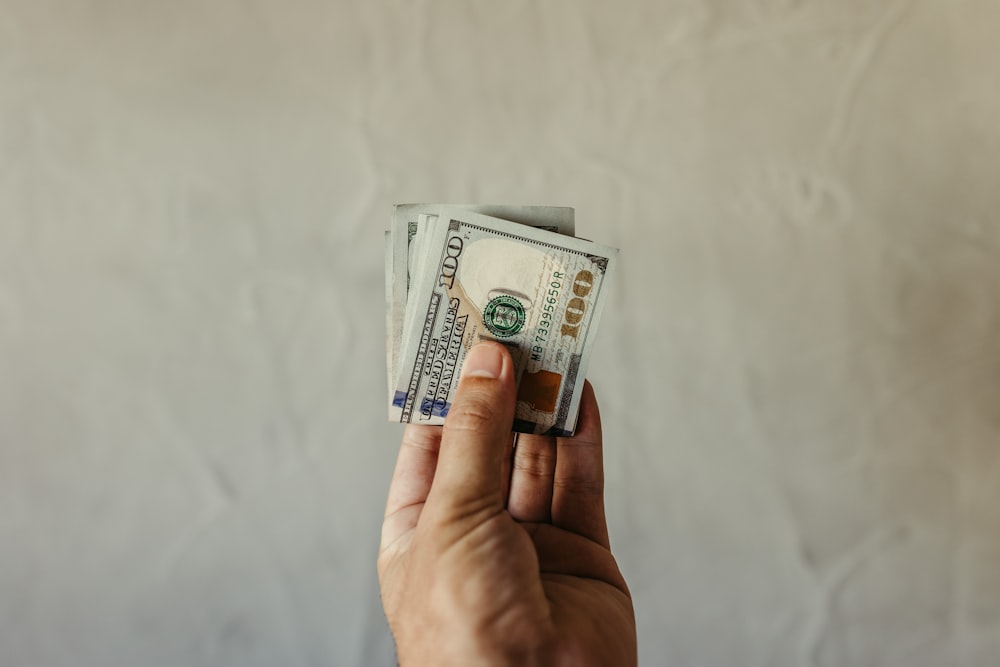 a person holding a stack of money in their hand