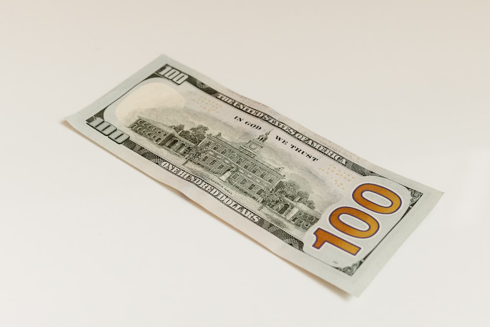 a one hundred dollar bill laying on a white surface