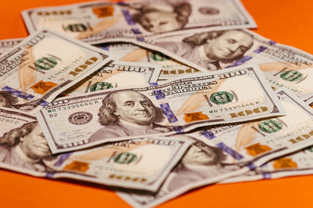 a pile of twenty dollar bills sitting on top of an orange table