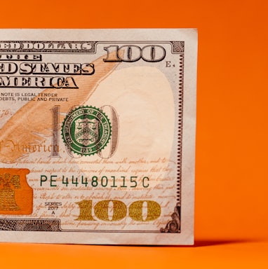 a one hundred dollar bill on an orange background