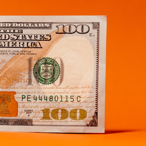 a one hundred dollar bill on an orange background