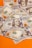 A collection of US one hundred dollar bills spread out on an orange surface. The bills feature the portrait of Benjamin Franklin and display details such as the security stripe, serial numbers, and Federal Reserve seal.