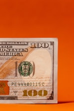 a one hundred dollar bill on an orange background