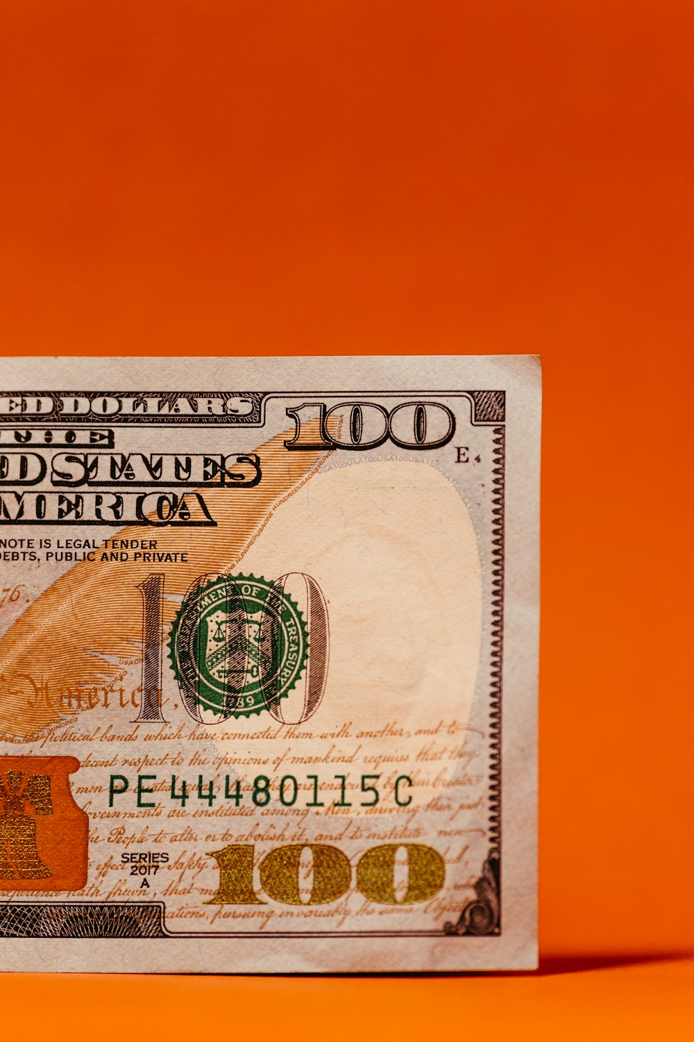 a one hundred dollar bill on an orange background