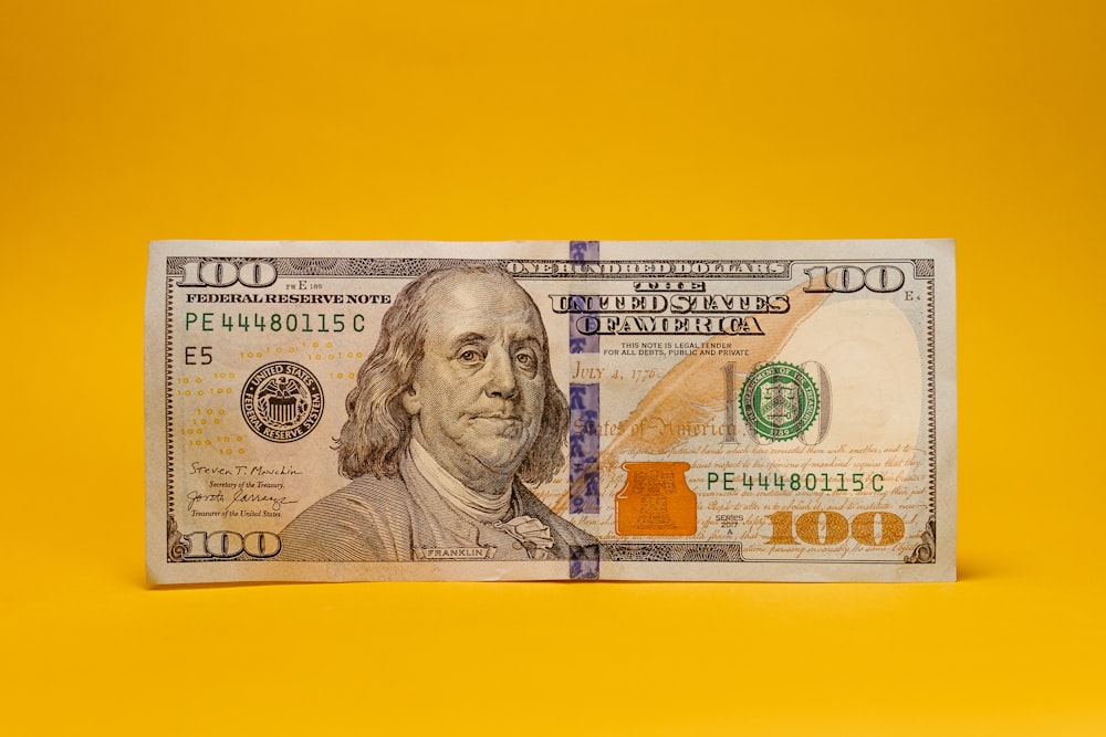 a one hundred dollar bill on a yellow background