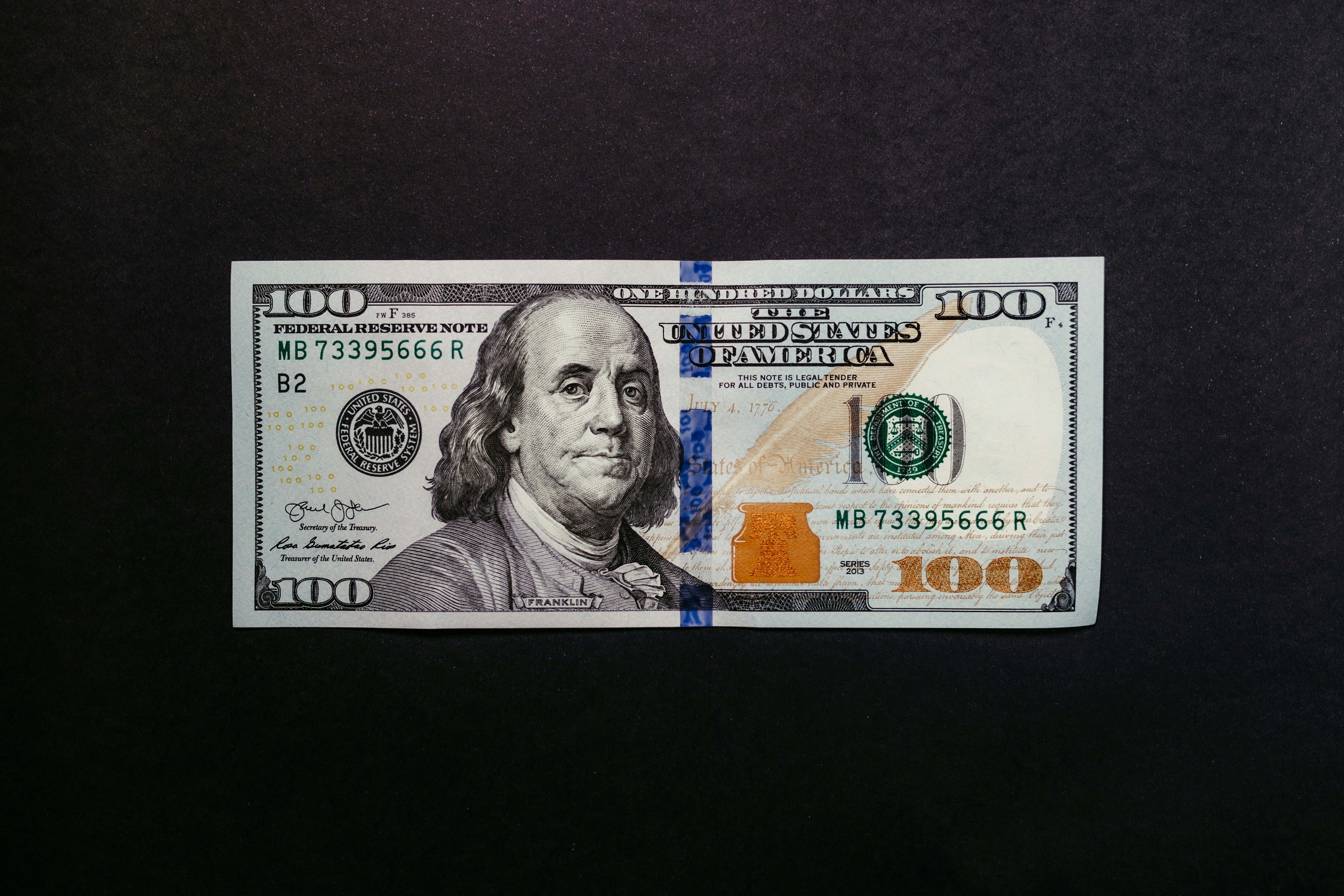 a one hundred dollar bill on a black background