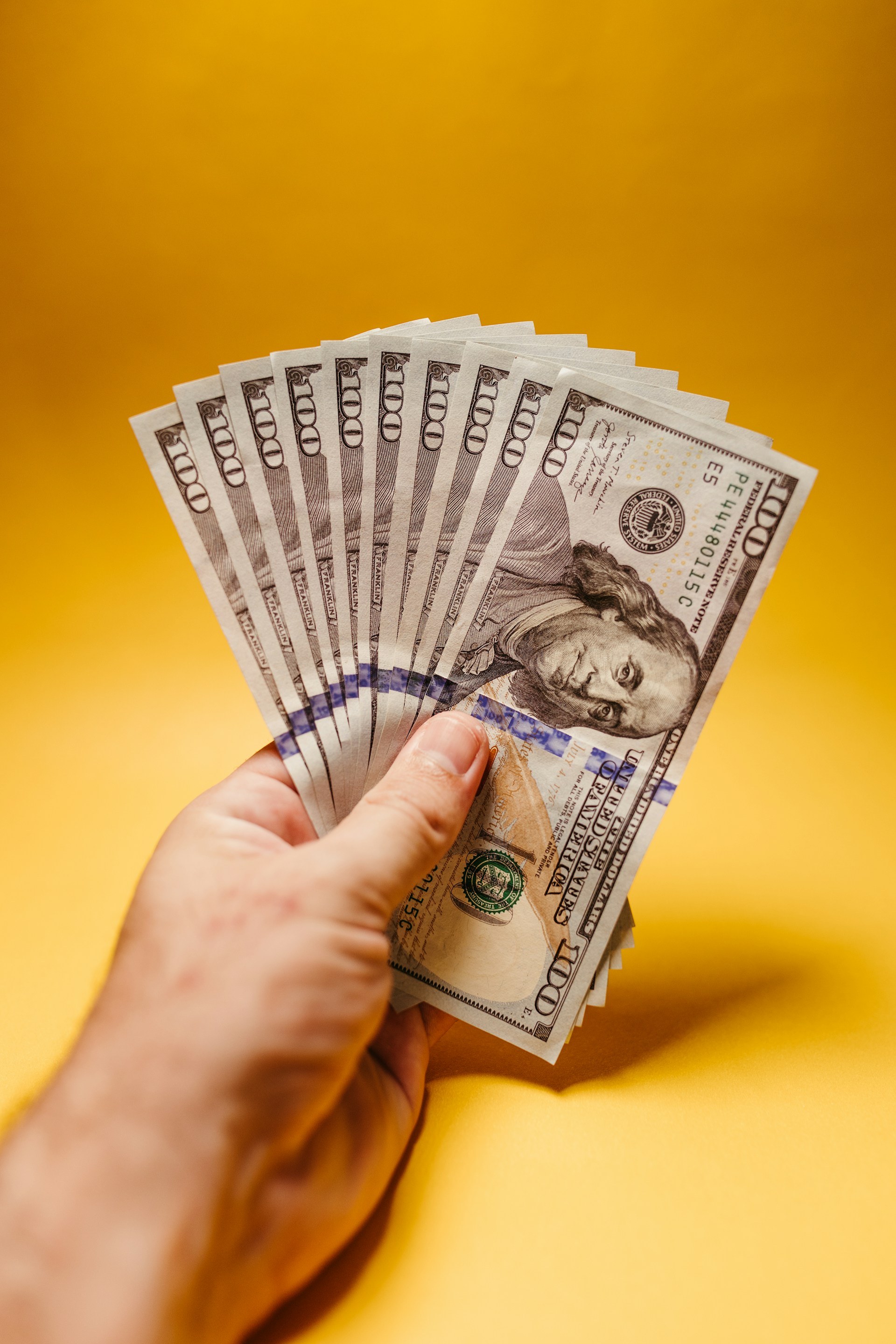 a hand holding a stack of twenty dollar bills