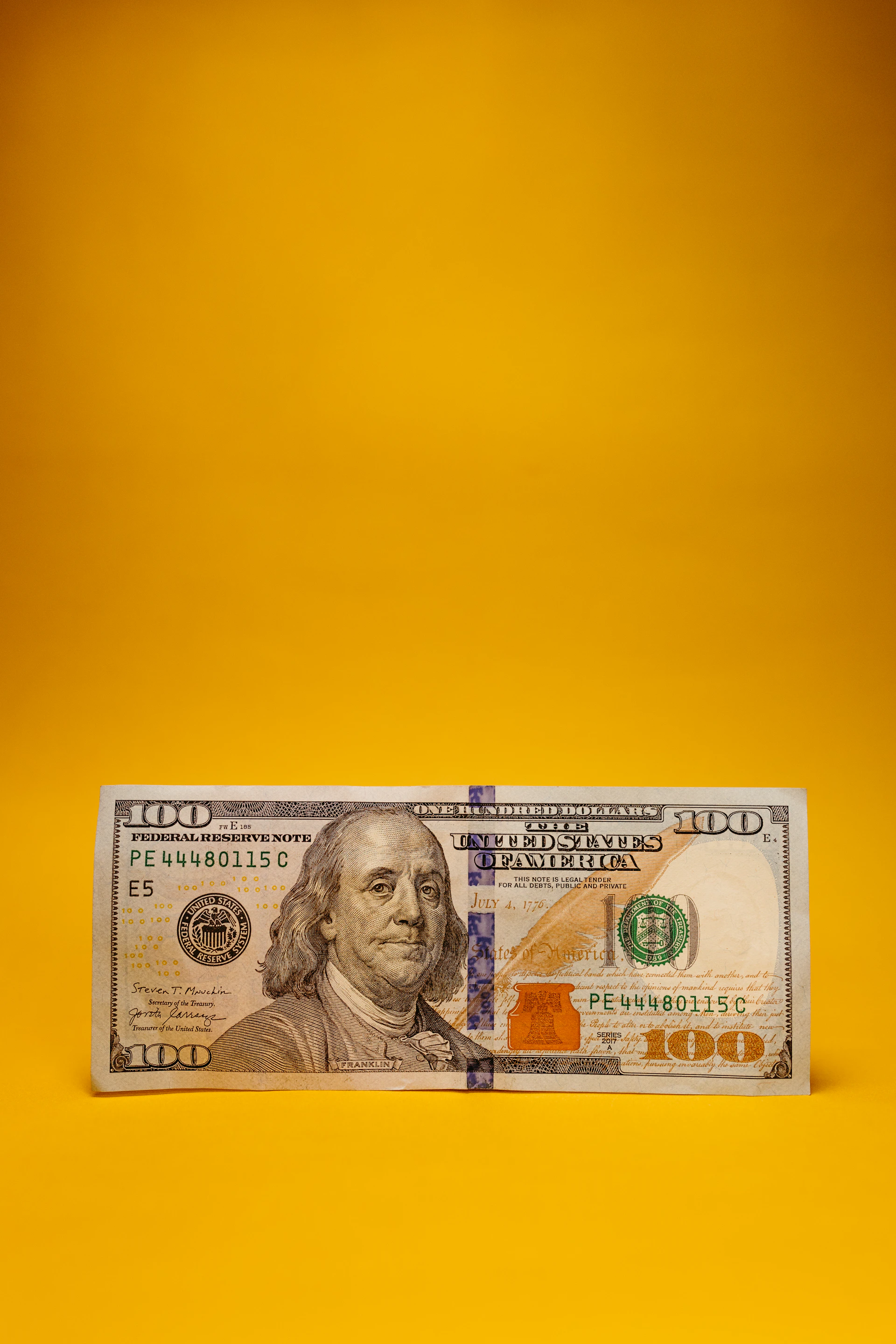 a one hundred dollar bill laying on a yellow background