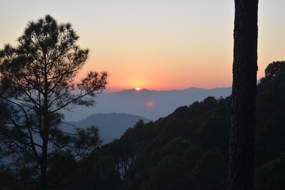 the sun is setting over the mountains in the distance