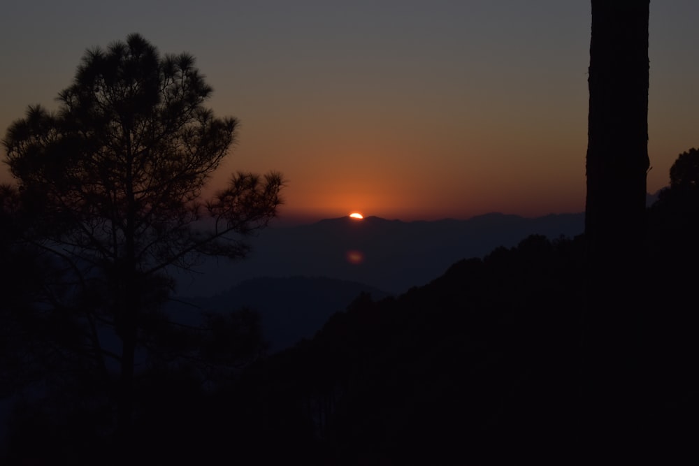 the sun is setting over a mountain range