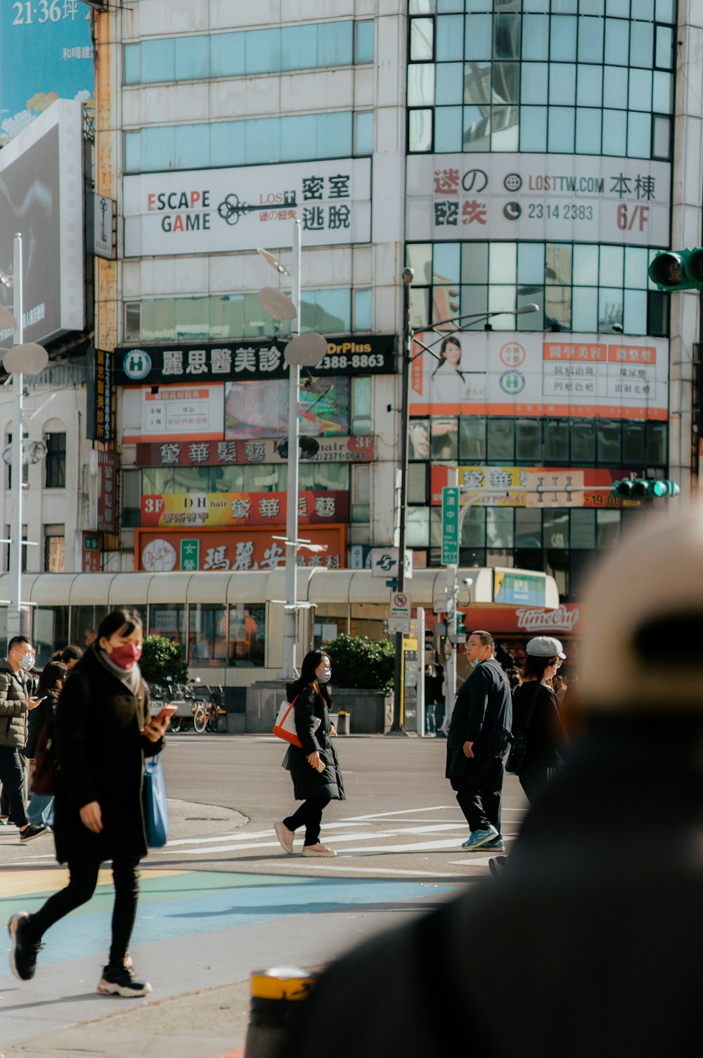 a group of people walking across a street next to tall buildings