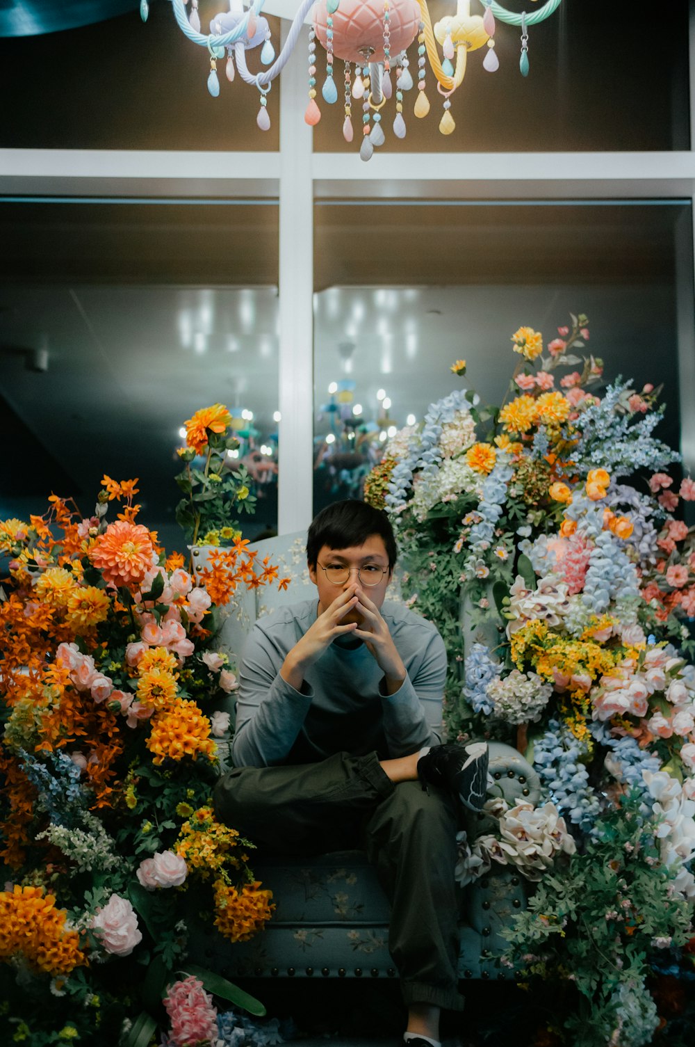 a man sitting on a bench surrounded by flowers