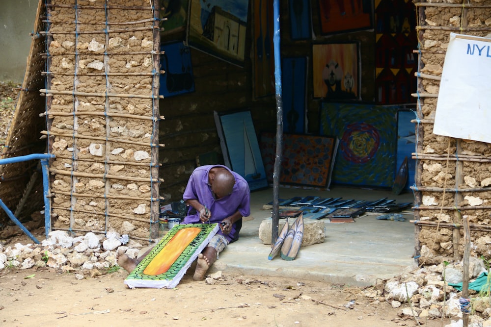 a man sitting on the ground in front of a building