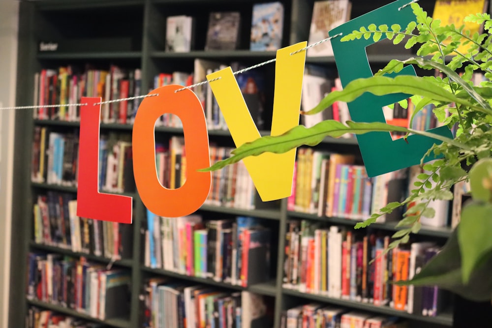 a love sign hanging from a string in front of a bookshelf