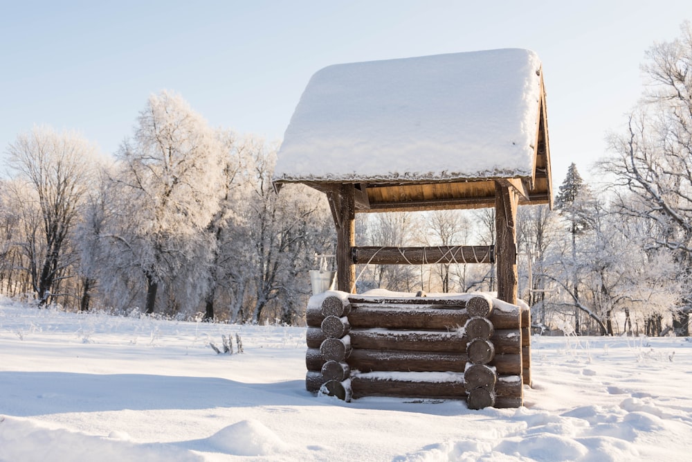 uma pilha de troncos sentados na neve ao lado de uma estrutura de madeira