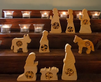 a set of wooden nativity figurines with candles in the background