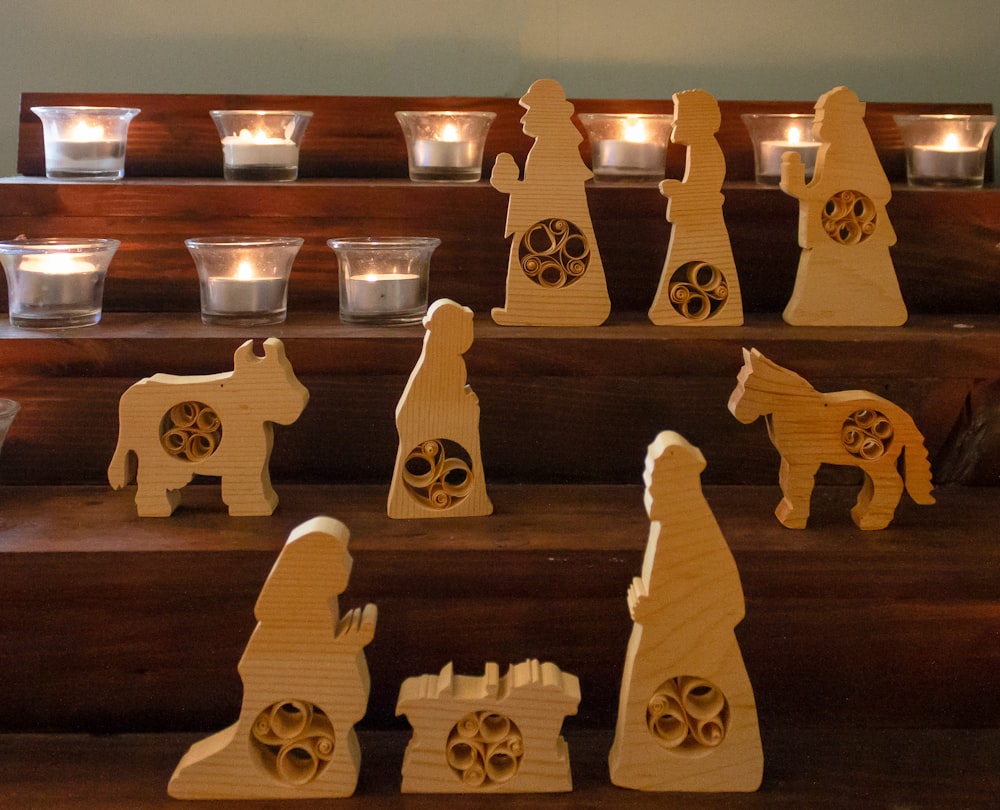 a set of wooden nativity figurines with candles in the background