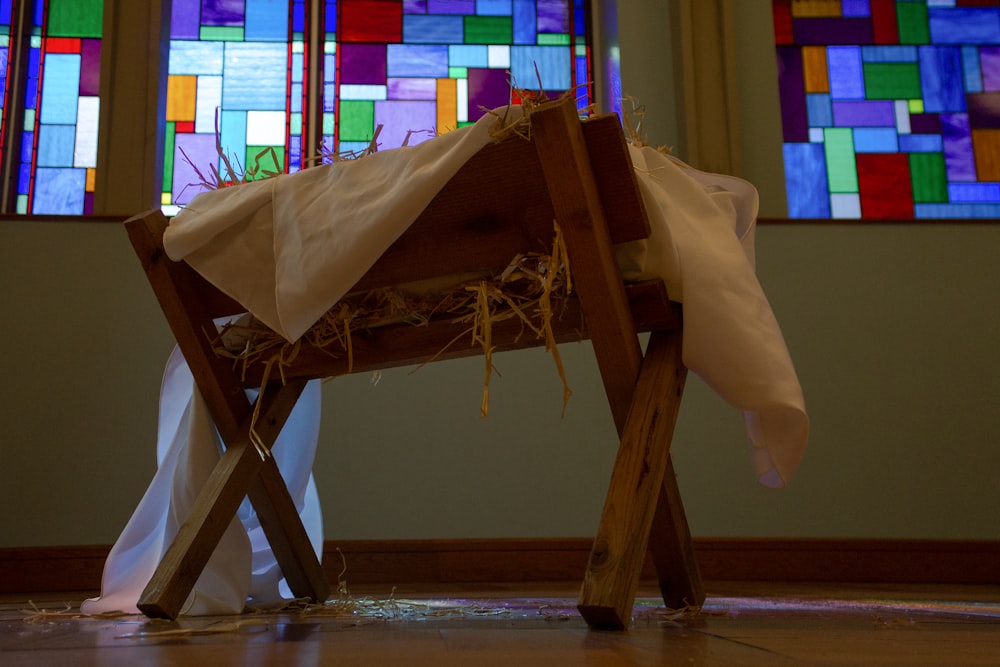 a wooden bench with a cloth draped over it in front of a stained glass window