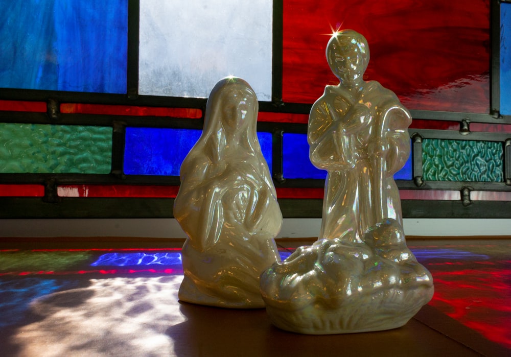 a statue of a person holding a child in front of a stained glass window