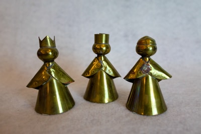 Delicate brass figurines shining under soft lighting on a wooden shelf.