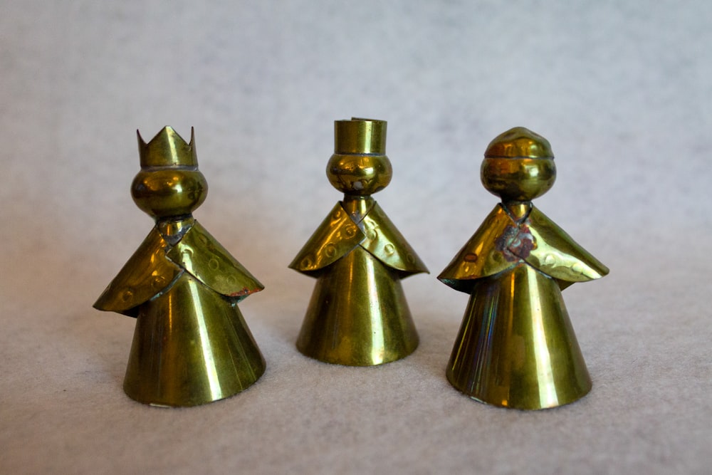 three gold colored metal figures on a white surface