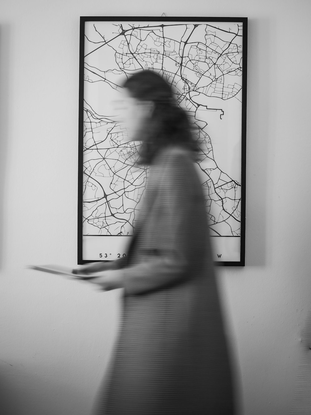 a blurry photo of a woman walking past a painting