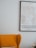 A cozy interior with a mustard yellow armchair partially visible next to a map of Copenhagen framed on a light-colored wall. The cushion and a pale flower bouquet add subtle detail to the scene.