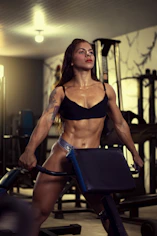 a woman in a bikini standing next to a gym machine