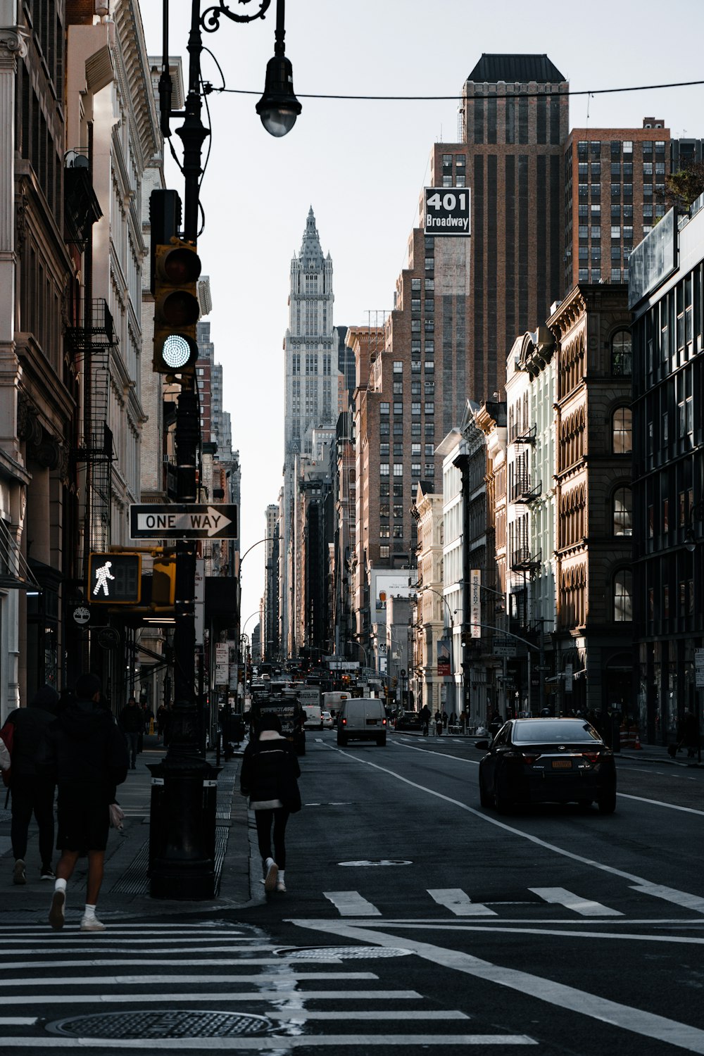 a couple of people walking down a street next to tall buildings