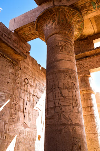 A detailed close-up of an ancient Egyptian hieroglyph carved into sandstone, glowing softly in warm sunlight.