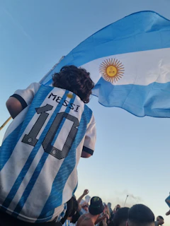 A passionate fan holding a Sportivo Luqueño flag wearing the official remera