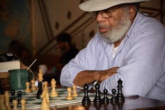 an older man playing chess with a large set of chess pieces